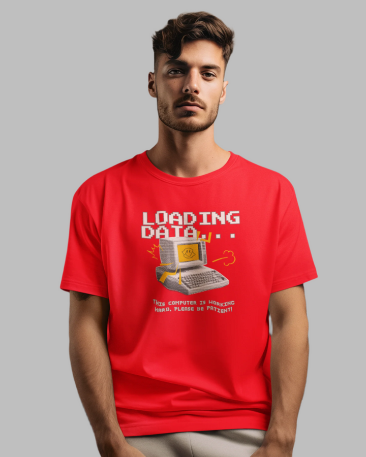 Man wearing a red t-shirt with a computer graphic and text in front of a piano.